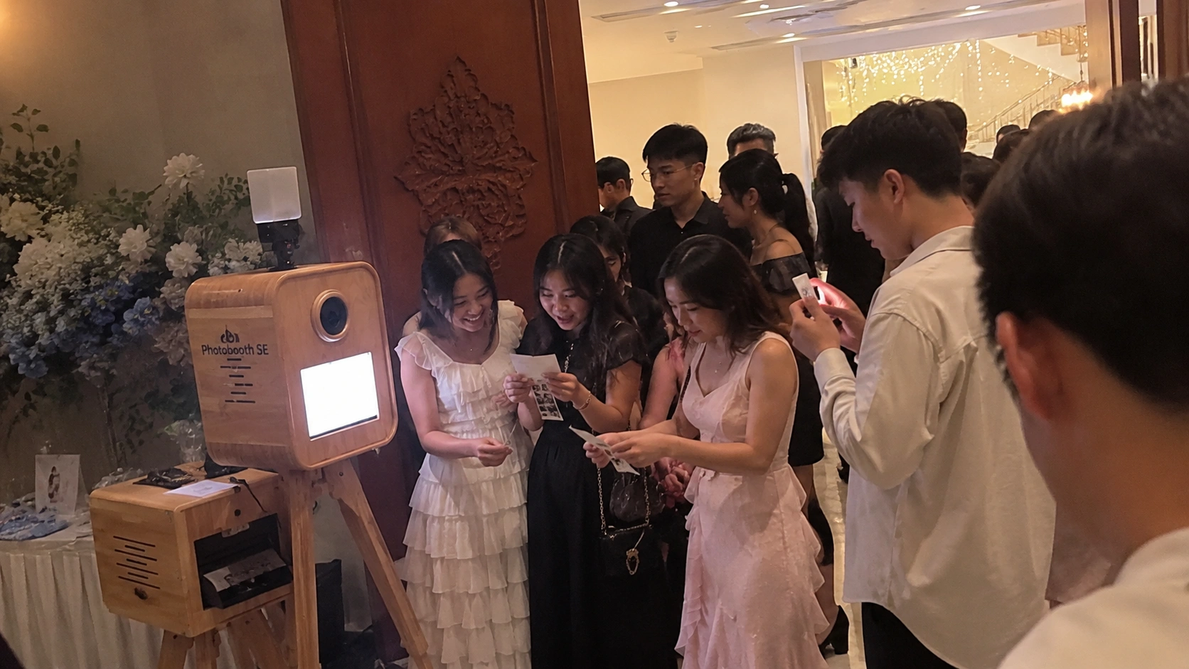 Góc photobooth gỗ truyền thống đặt cạnh lối vào tiệc cưới ngoài trời tại Nha Trang