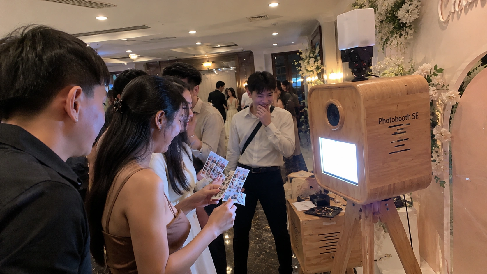 Trang trí backdrop hoa tươi và đèn dây cho góc photobooth gỗ tại tiệc cưới ngoài trời Nha Trang