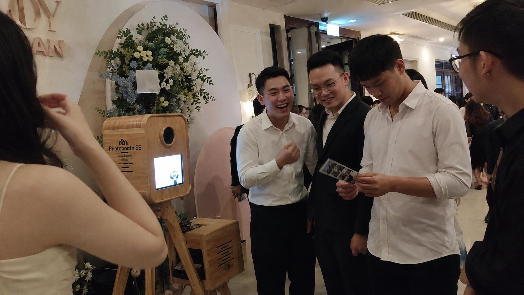 Khách mời xếp hàng chụp ảnh tại góc photobooth gỗ trong tiệc cưới ngoài trời ở Nha Trang